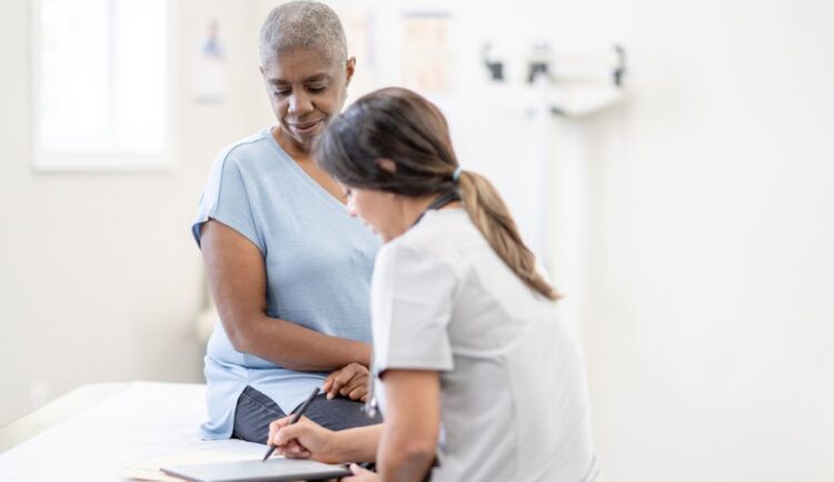 an older patient speaks with her doctor; they're looking at a tablet together; evokes discussing treatment options